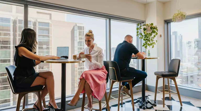 Client working at high tables in a professional coworking space with a stunning city view.