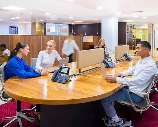 Clients working and chatting on Cisco phones in a professional coworking space at Mayfair.